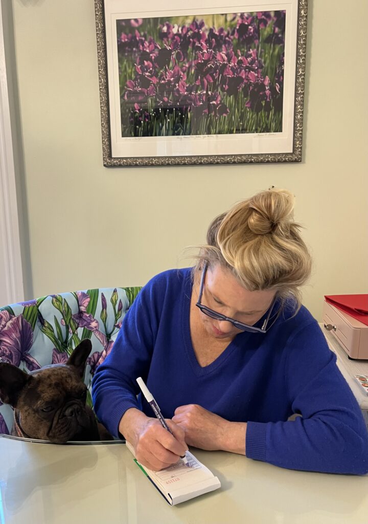 Nancy writing with her dog in the bloom room shop